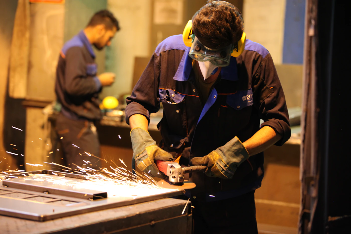 Fabrication worker in safety goggles using a grinder